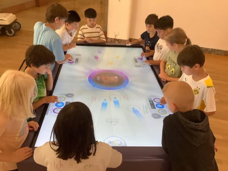 Interaktive Lernumgebung mit Kindern an einem digitalen Tisch im Museum König.